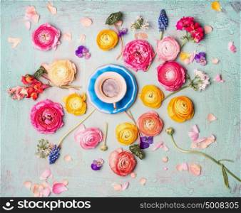 Cup of coffee with colorful flowers on turquoise blue shabby chic background, top view, flat lay