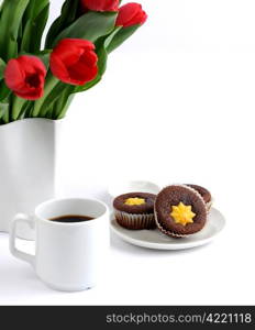 Cup of coffee with cookies and flowers on a white background.