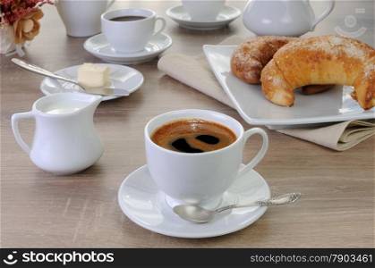 Cup of coffee with croissants, butter and milk on the table