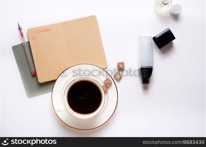 cup of coffee with diary, and care cosmetics  around white background. life style flat lay