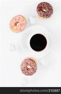 Cup of coffee with donuts and meringues in motion on white background