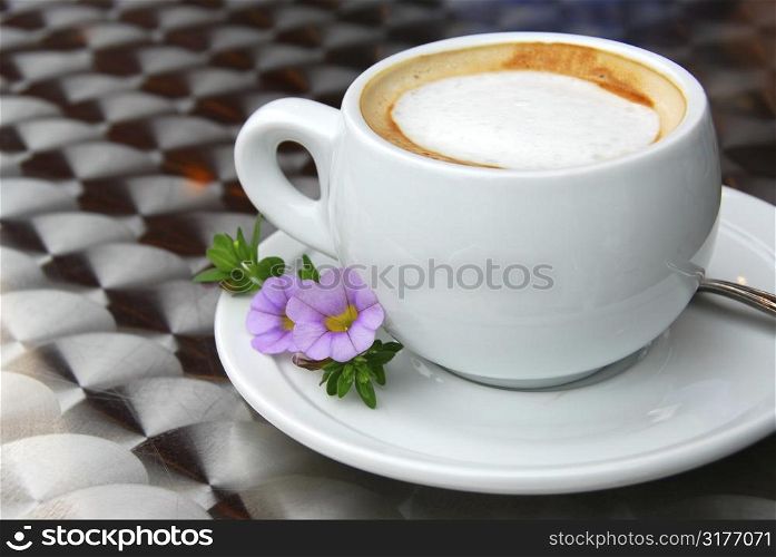 Cup of coffee with flowers on saucer