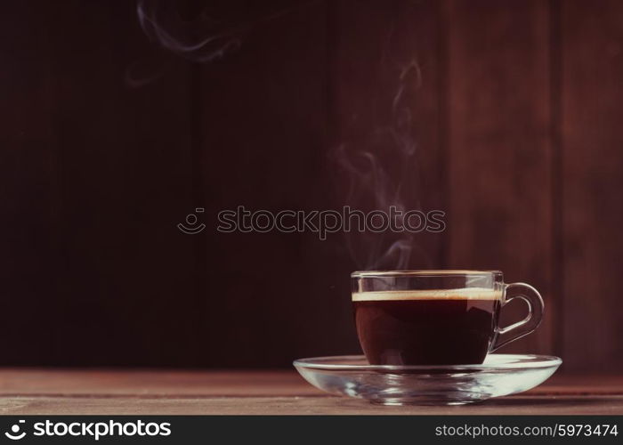 Cup of coffee with fume on the wooden background. Cup of coffee with fume