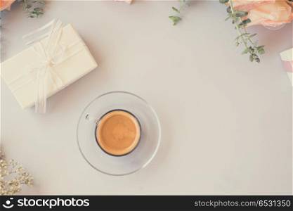 Cup of coffee with gift or present box and flowers on blue table from above, retro toned. Styled desktop scene. Styled desktop scene