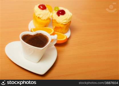 Cup of coffee with gourmet delicious cookie cake with sweet cream and fruits as dessert food on top served with orange on plate. Breakfast on board.