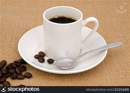 Cup of coffee with grains on Sackcloth mesh background.
