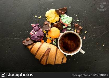 Cup of coffee with macarons and croissant on black stone table