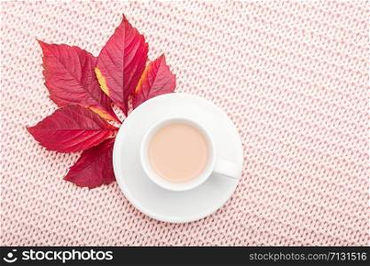 Cup of coffee with milk and red autumn leaves on pastel pink knitted plaid background. Autumn cozy concept. Flat lay, top view, copy space.. Cup of coffee with milk and red autumn leaves on pastel pink knitted plaid background. Autumn cozy concept. Flat lay, top view, copy space