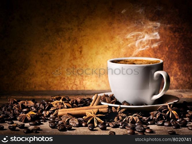 Cup of coffee with spices on orange background
