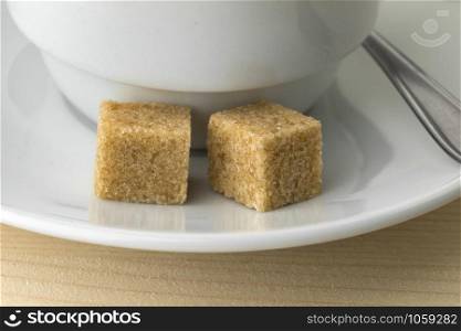 Cup of coffee with two fairtrade cane sugar cubes close up