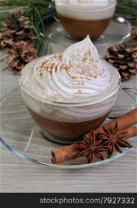 Cup of coffee with whipped cream and cinnamon on the table with pine cones