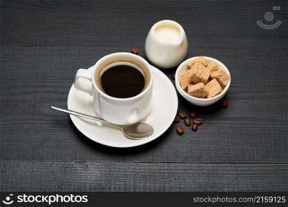 Cup of espresso coffee and pot of cream or milk on dark wooden background.. Cup of espresso coffee and pot of cream or milk on dark wooden background