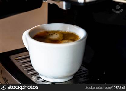 Cup of espresso while the cup is filling in a coffee machine