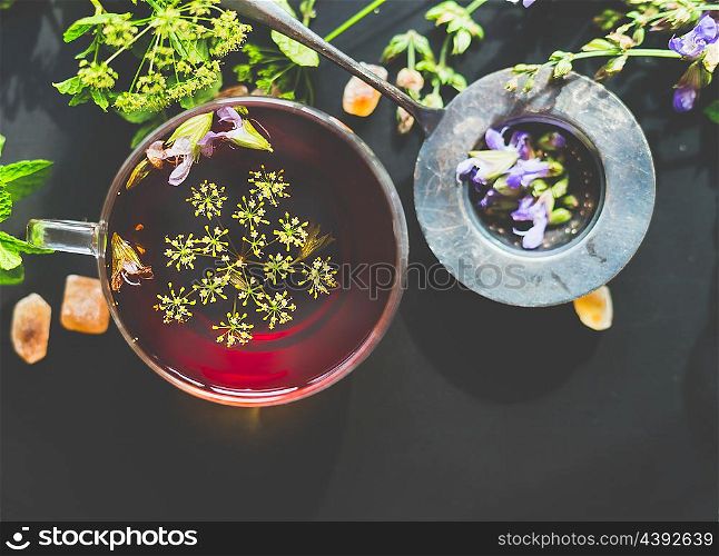 Cup of fennel tea and strainer on dark rustic background, top view