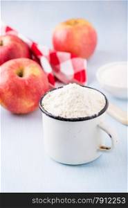 Cup of flour and red apples. Ingredients for baking. Selective focus
