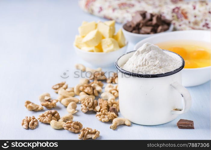 Cup of flour, eggs, butter, nuts and chocolate chunks. Ingredients for baking. Selective focus, copy space