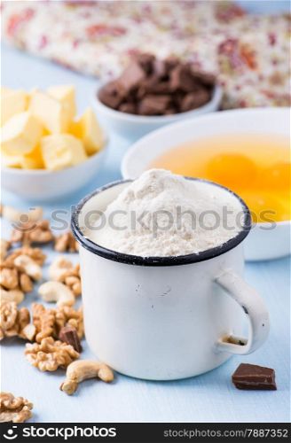 Cup of flour, eggs, butter, nuts and chocolate chunks. Ingredients for baking. Selective focus