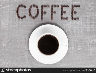 Cup of fresh coffee with sign made from beans on wooden background for cafe