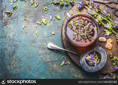 Cup of fresh herbal tea with healing herbs and flowers on aged rustic background, top view, place for text