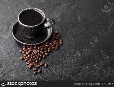 Cup of fresh raw organic coffee with beans on black background. Top view. Black ceramic mug.