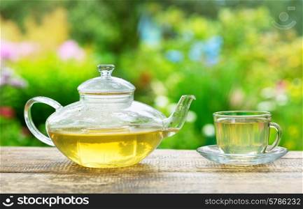 cup of green tea and teapot on wooden table