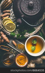 Cup of healthy turmeric spice tea with iron teapot and ingredients:  lemon,  ginger, cinnamon sticks and honey , top view.  Immune boosting remedy , detox and herbal medicine