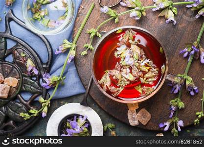 Cup of herbal tea with fresh herbs and aged vintage tea set, top view, close up. Healthy ,healing or detox drinks concept
