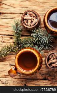 Cup of herbal tea with pine buds on wooden background.Mug of herbal tea on aged rustic background. Tea with pine buds