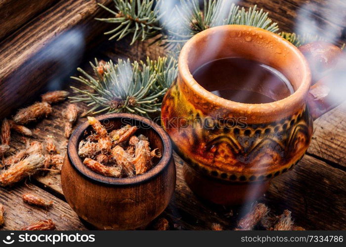 Cup of herbal tea with pine buds on wooden background. Tea with pine buds