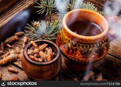 Cup of herbal tea with pine buds on wooden background. Tea with pine buds