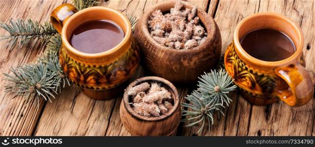 Cup of herbal tea with pine buds on wooden background. Tea with pine buds