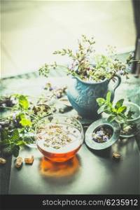 Cup of herbal tea with tea tools and fresh herbs plant on terrace or garden table . Healthy drinks, detox or clean food concept