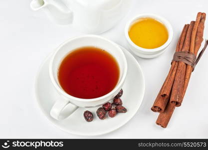 Cup of hot berries tea with cinnamon sticks, and honey