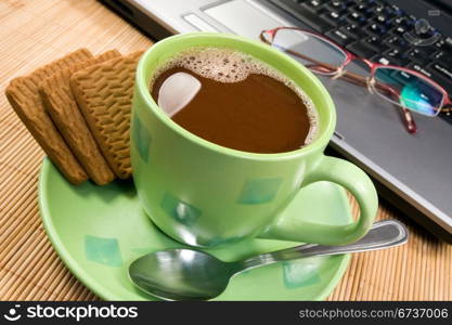 cup of hot cacao, biscuits and computer