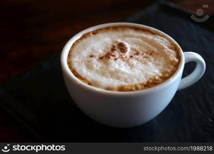 cup of hot cappuccino coffee on wooden table