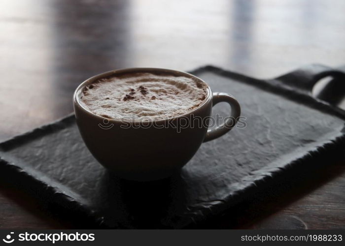 cup of hot cappuccino coffee on wooden table