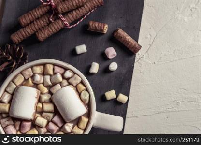 Cup of hot chocolate filled with marshmallows. Chocolate sticks on a wooden plate. Above view with copy space.