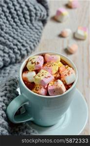 cup of hot chocolate with marshmallows and winter scarf