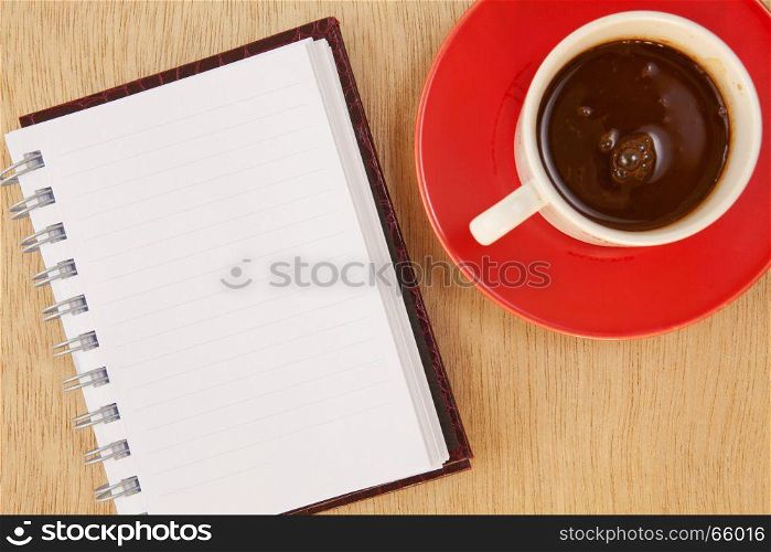 cup of hot coffee and book on wood background