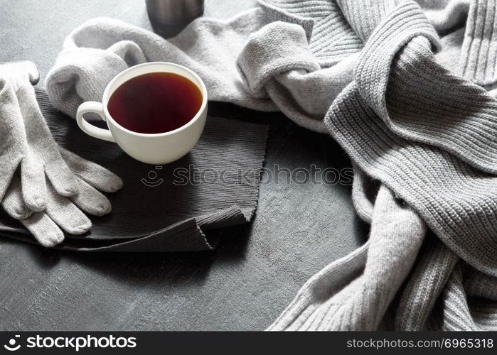 Cup of hot coffee on a black table, close up photo warm sweater with mug, winter morning concept, top view. Cup of hot coffee on a black table