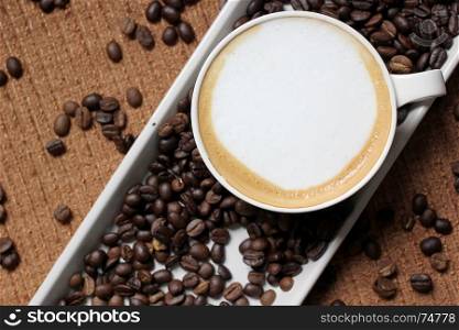 cup of hot coffee on coffee beans