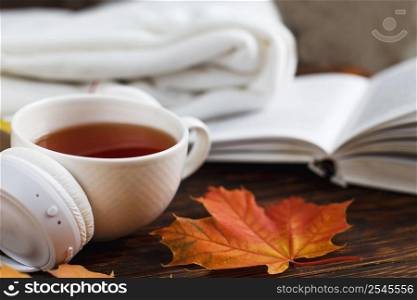 Cup of hot coffee or tea with autumn leaves and headphones on a brown wooden background. A Cup of hot coffee or tea with autumn leaves and headphones on a brown wooden background
