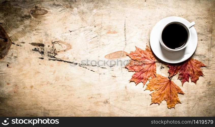 Cup of hot coffee with autumn leaves. On wooden background.. Cup of hot coffee with autumn leaves.