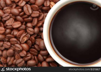 cup of hot coffee with coffee beans in the background