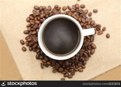 cup of hot coffee with roasted coffee on burlap sack