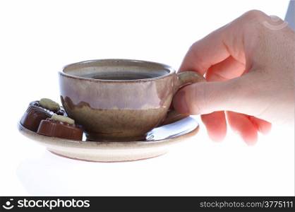 Cup of hot drink beverage coffee or tea and chocolate pralines in human hand
