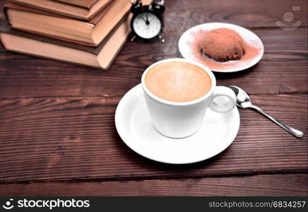 Cup of hot espresso, behind stack of books, top view