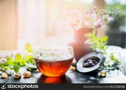 Cup of hot herbal tea on window still at sunny nature background, horizontal. Home scene with hot drink. Detox or clean food concept