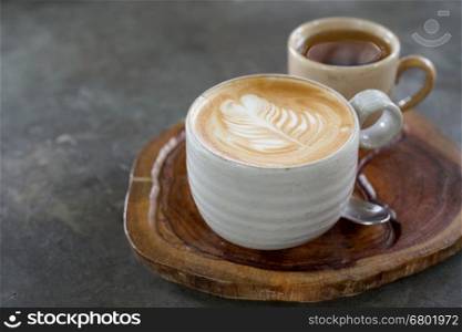 cup of hot latte art coffee on wooden plate