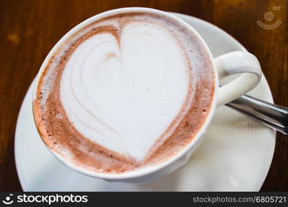 cup of hot latte art coffee on wooden table